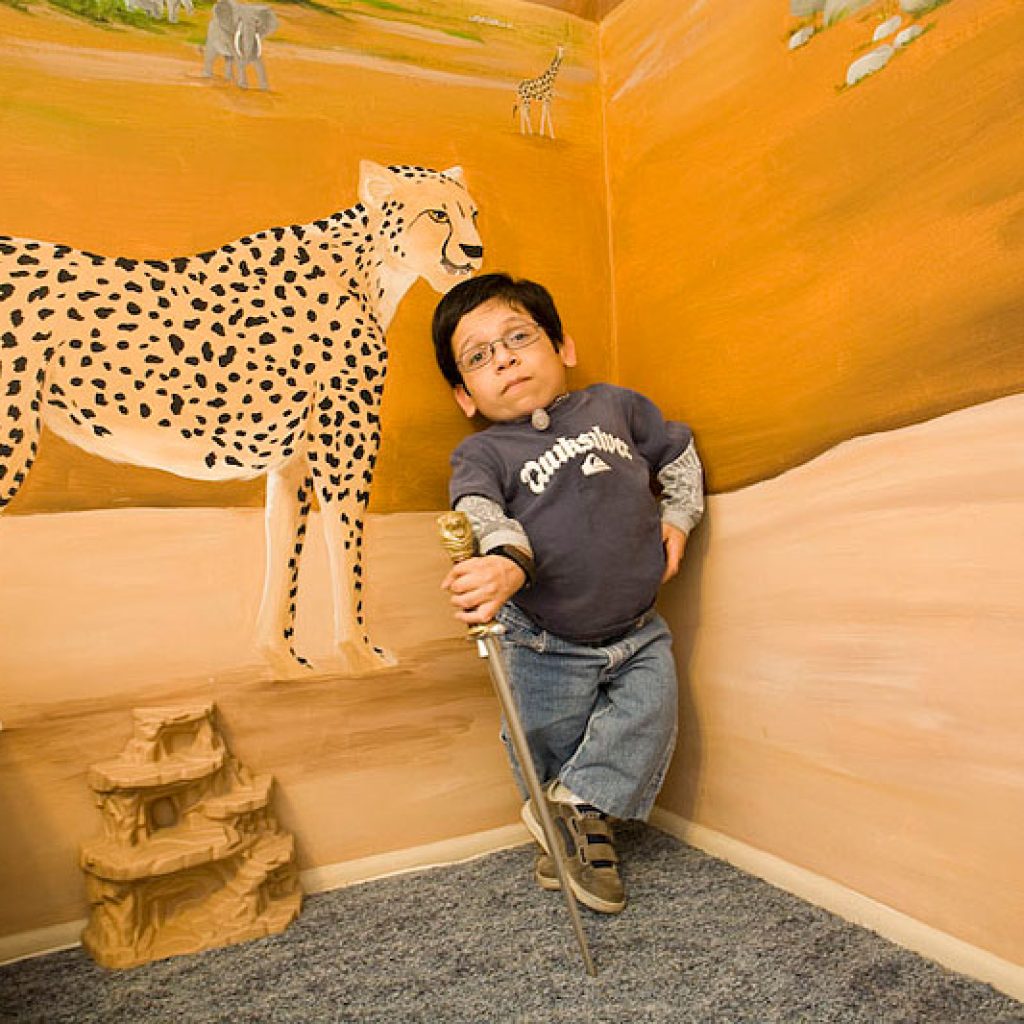 Gabe posing with a sword in front of a cheetah mural