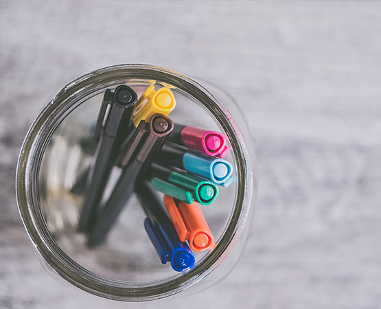 Multicolored markers in a glass jar