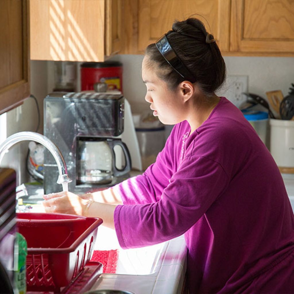 Supported individual washing her hands in her own home