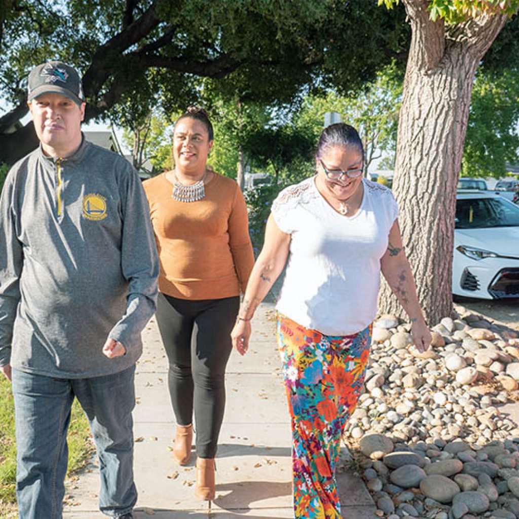 Two JNCS staff and supported individual taking a walk down the sidewalk