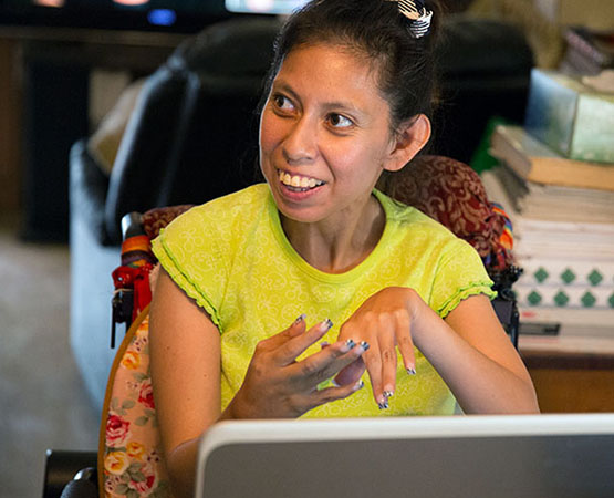 Woman at a laptop smiling to someone to her right