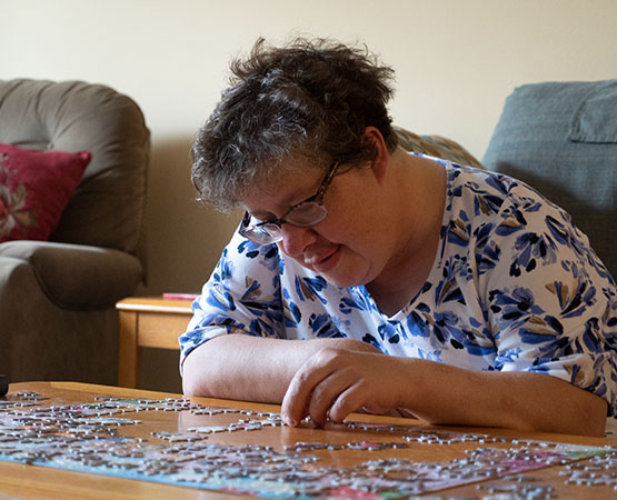 Woman working on a jigsaw puzzle at a table
