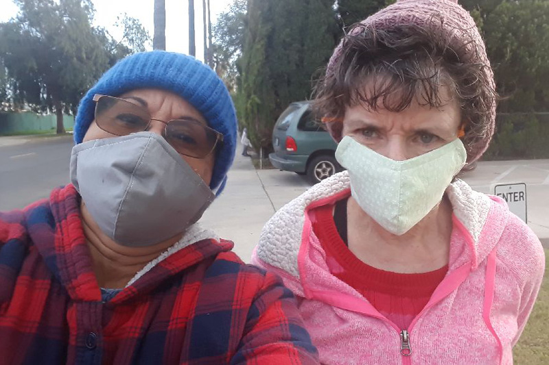 two women wearing face masks looking at the camera