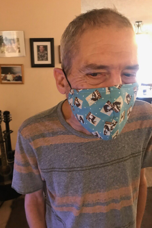 Older man in a striped shirt wearing a blue facemask