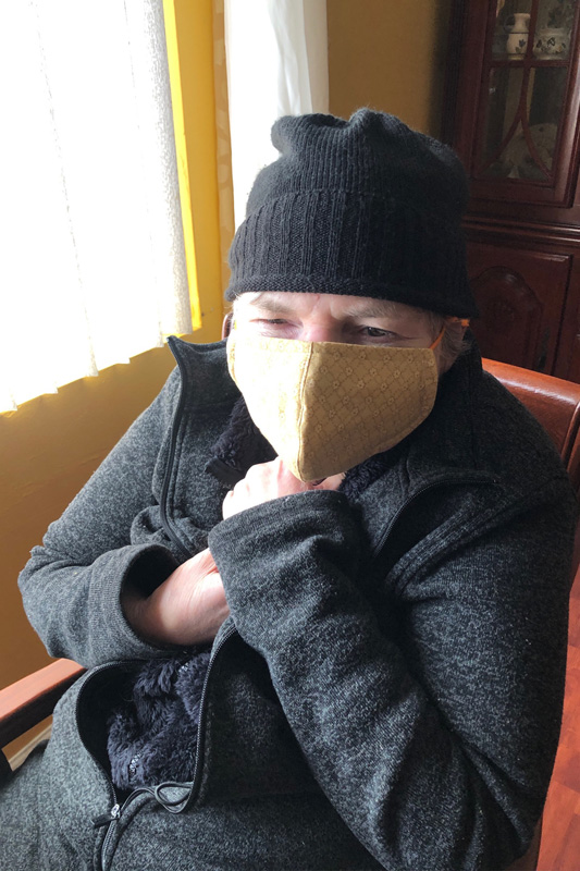 Man in a grey sweater and black beanie wearing a yellow facemask