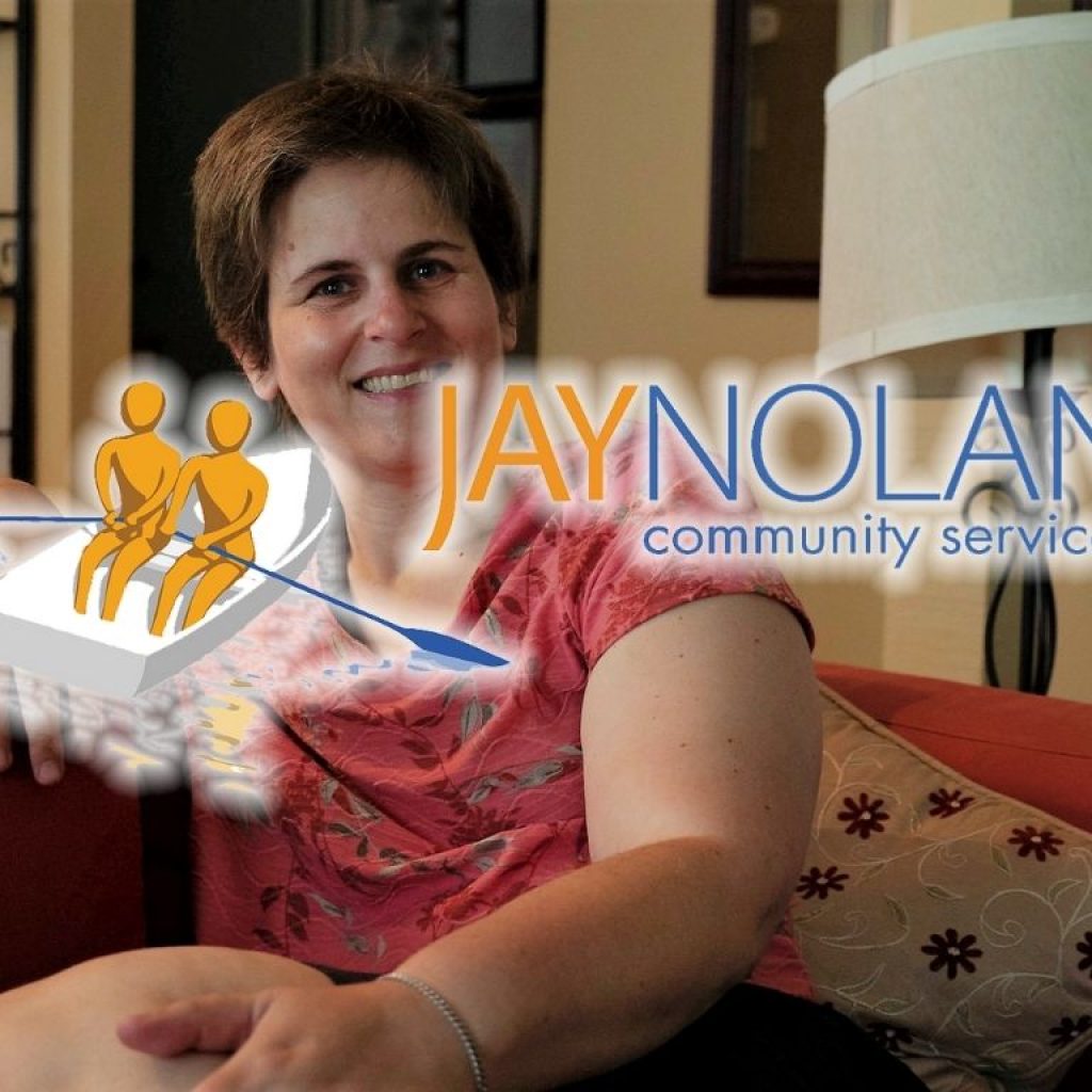 Woman sitting on a couch in her living room with JNCS logo overlaid