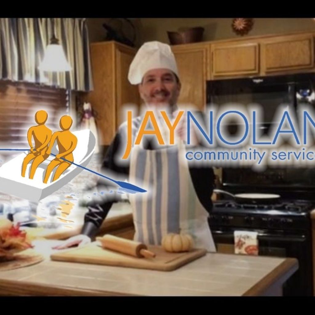 JNCS CEO wearing an apron in a kitchen and smiling candidly at the camera with JNCS logo overlaid