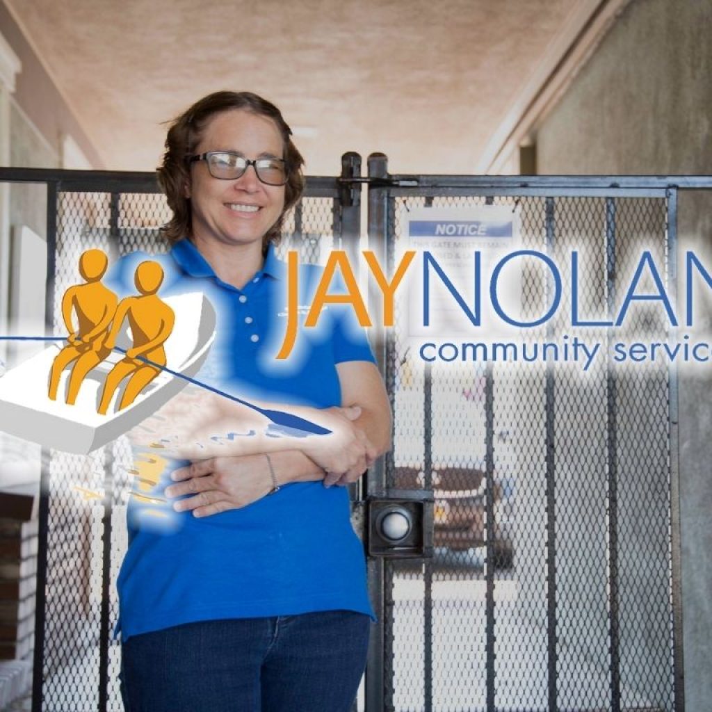 JNCS supported individual in her work uniform smiling next to a gate