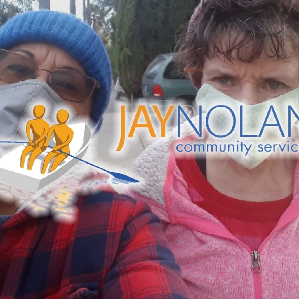 two women wearing face masks looking at the camera with JNCS logo overlaid