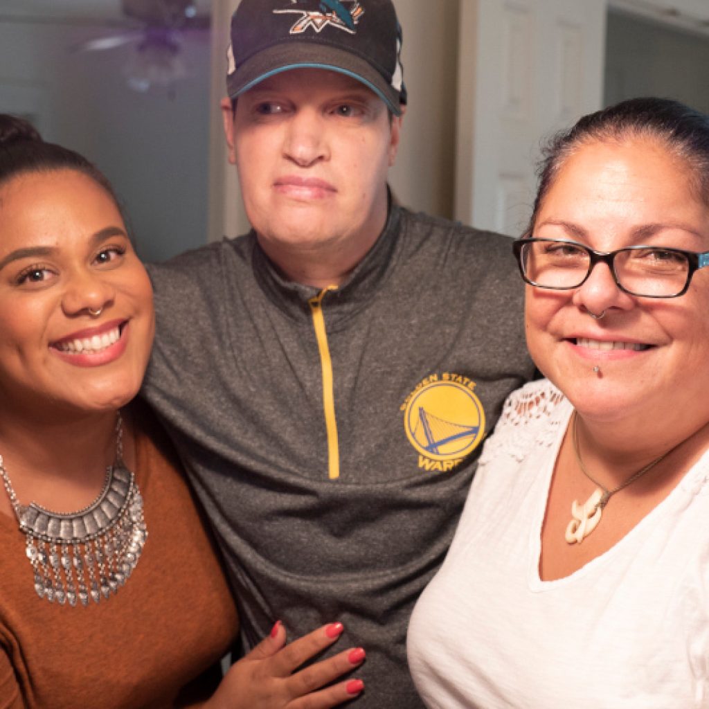 A man embracing two women in a group hug.