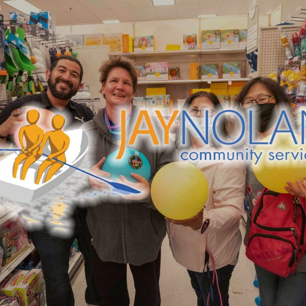 Four people holding up multi-colored balls at a store with Jay Nolan Community Services logo overlaid