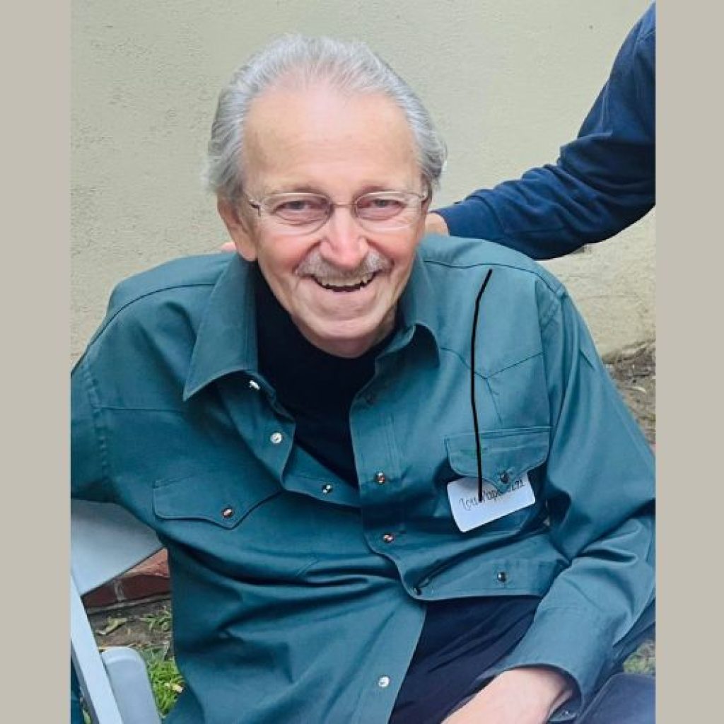 Louis Paparozzi, an elderly Caucasian man with a great smile. He is sitting down and wearing a dark green button-down shirt.