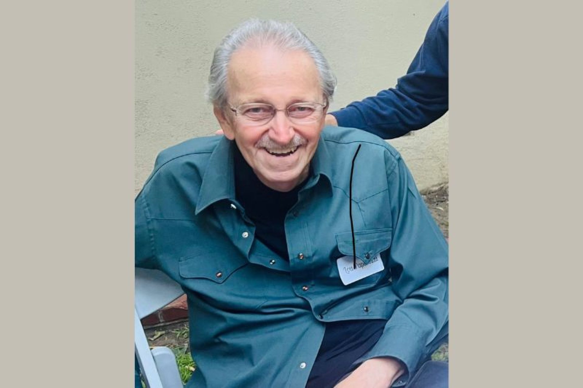 Louis Paparozzi, an elderly Caucasian man with a great smile. He is sitting down and wearing a dark green button-down shirt.