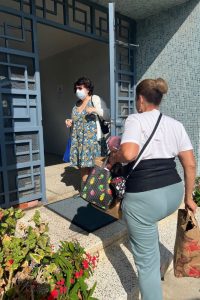 Ilene holds the building's door open for Marisol