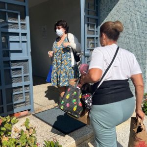 Ilene holds the building's door open for Marisol