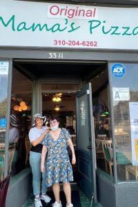 Marisol and Ilene standing and smiling in front of one of their favorite restaurants