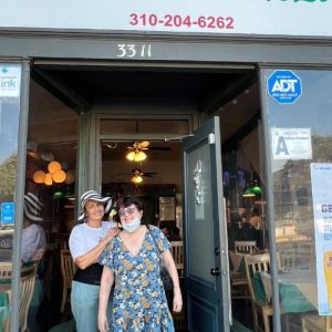 Marisol and Ilene standing and smiling in front of one of their favorite restaurants