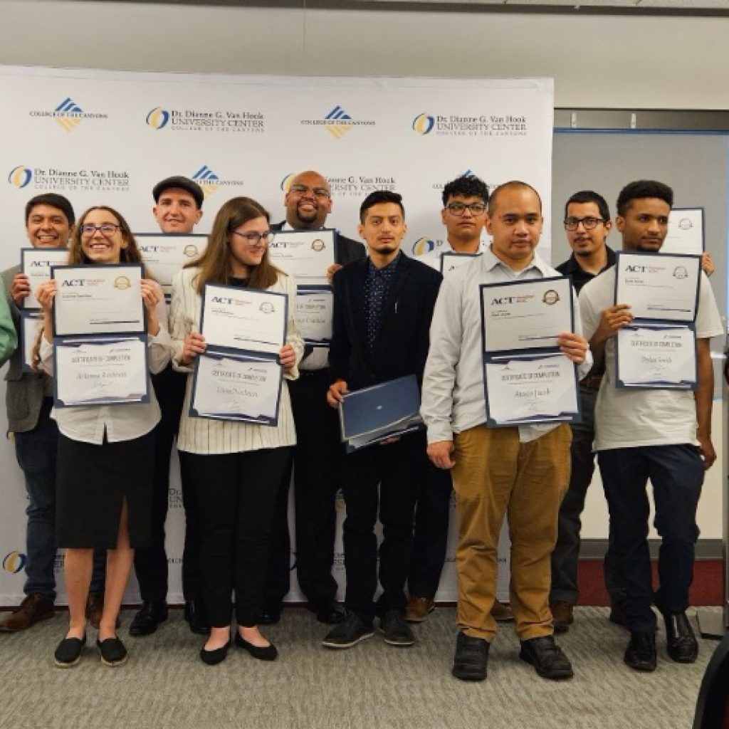 A group of 11 young men and women hold up their graduation certificated for the Uniquely Abled Academy's CNC machining program.