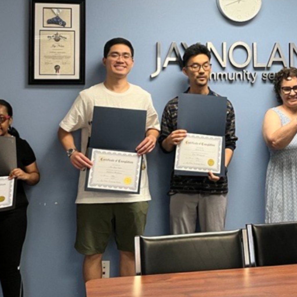 Four young adults (two male and two female) hold up their graduation certificates from the JNCS Soft Skills Employment Preparation Training Program.