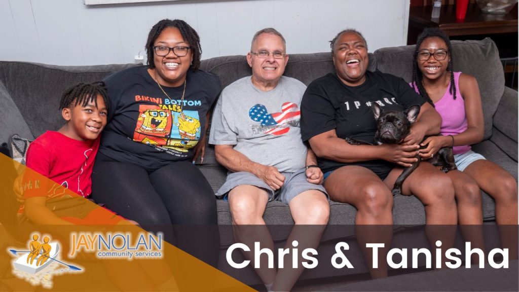 Video thumbnail of a family sitting on a grey couch in their living room. Text reads: "Chris & Tanisha"