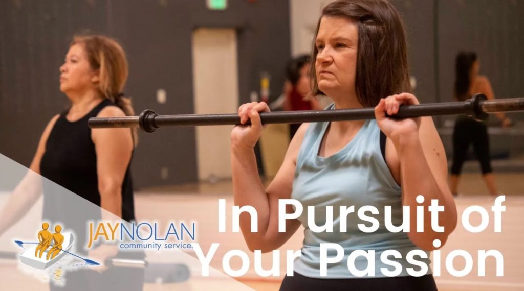 Video Thumbnail featuring a Caucasian woman in a light blue tank top lifting an exercise bar at a gym class. Text reads: "In Pursuit of Your Passion"