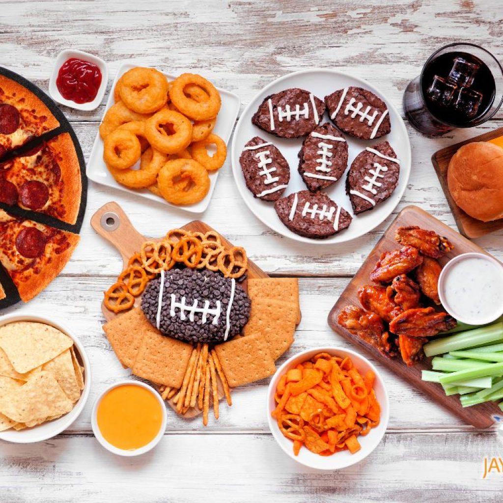 A spread of snacks and dips for a Superbowl party sitting on a wooden table