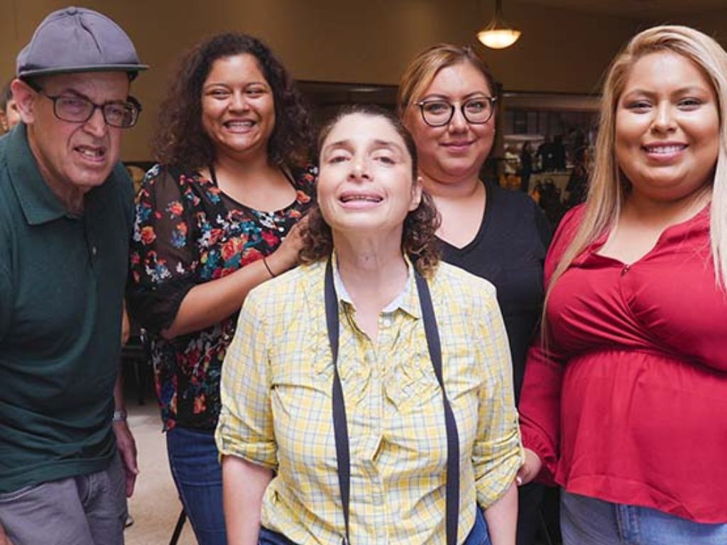 A group of four people of different genders and ethnicities posing for a group photo.