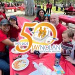 Families with kids sitting around a red picnic table. Jay Nolan Community Services 50 Year Anniversary logo overlaid.
