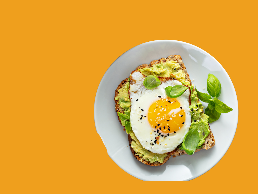 A breakfast plate on an orange background. Plate includes avocado toast with a fried egg on top.