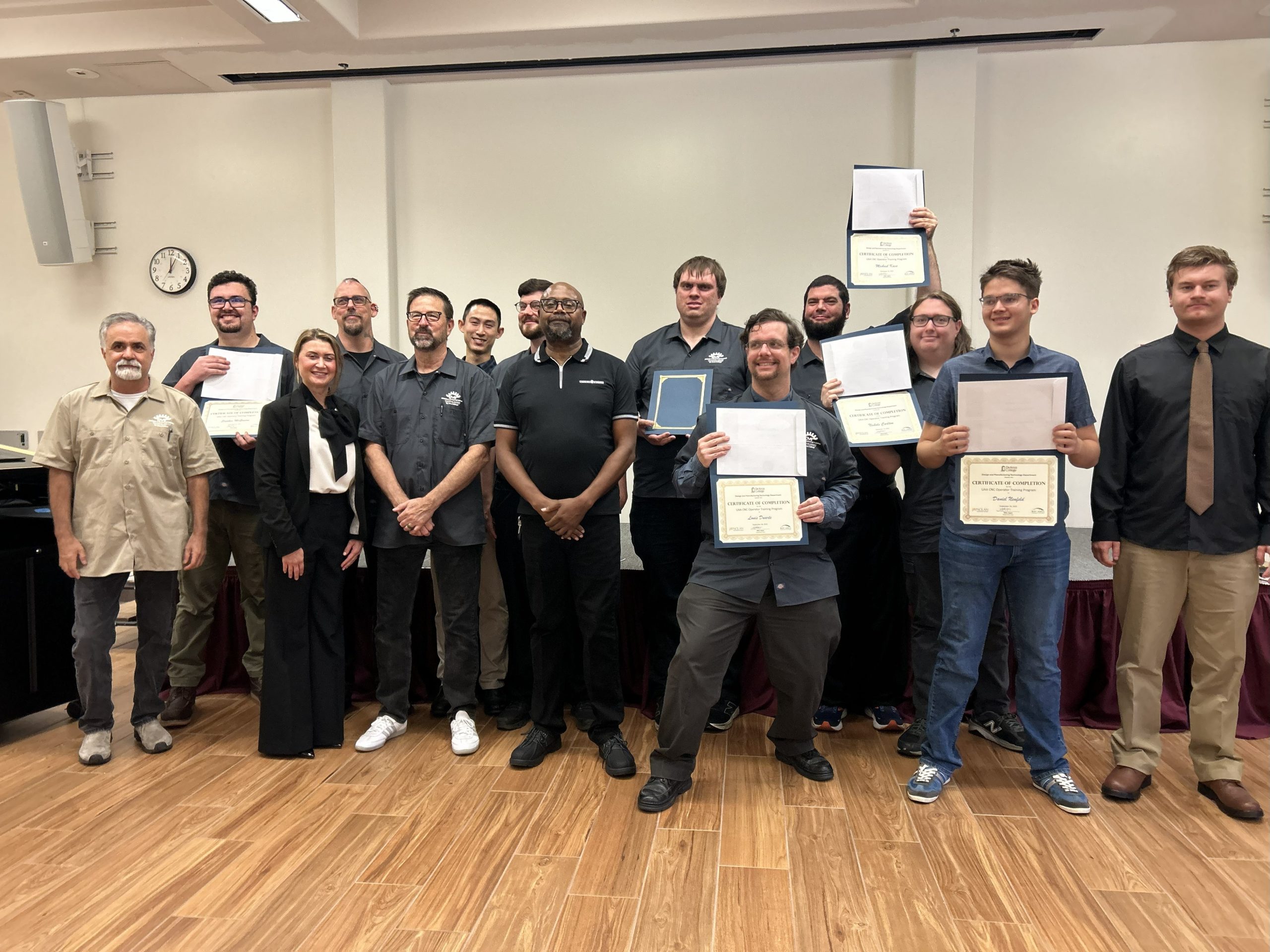 De Anza UAA instructors and students pose for a group photo during the UAA graduation. Students are holding up their certificates.