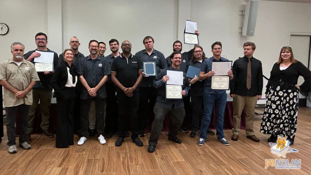 De Anza UAA instructors and students pose for a group photo during the UAA graduation. Students are holding up their certificates.