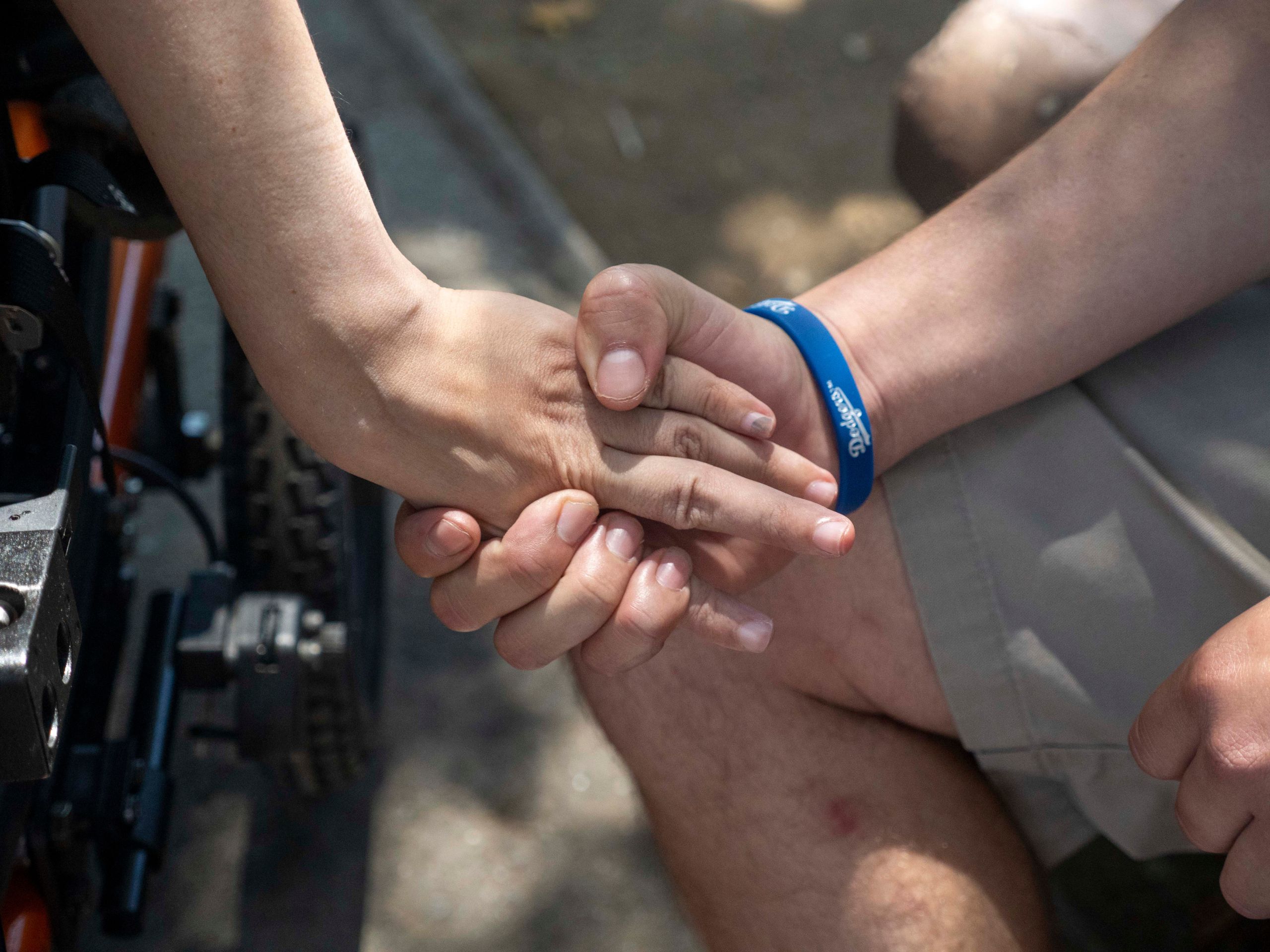 Two people holding hands, one has a blue wristband on the wrist.