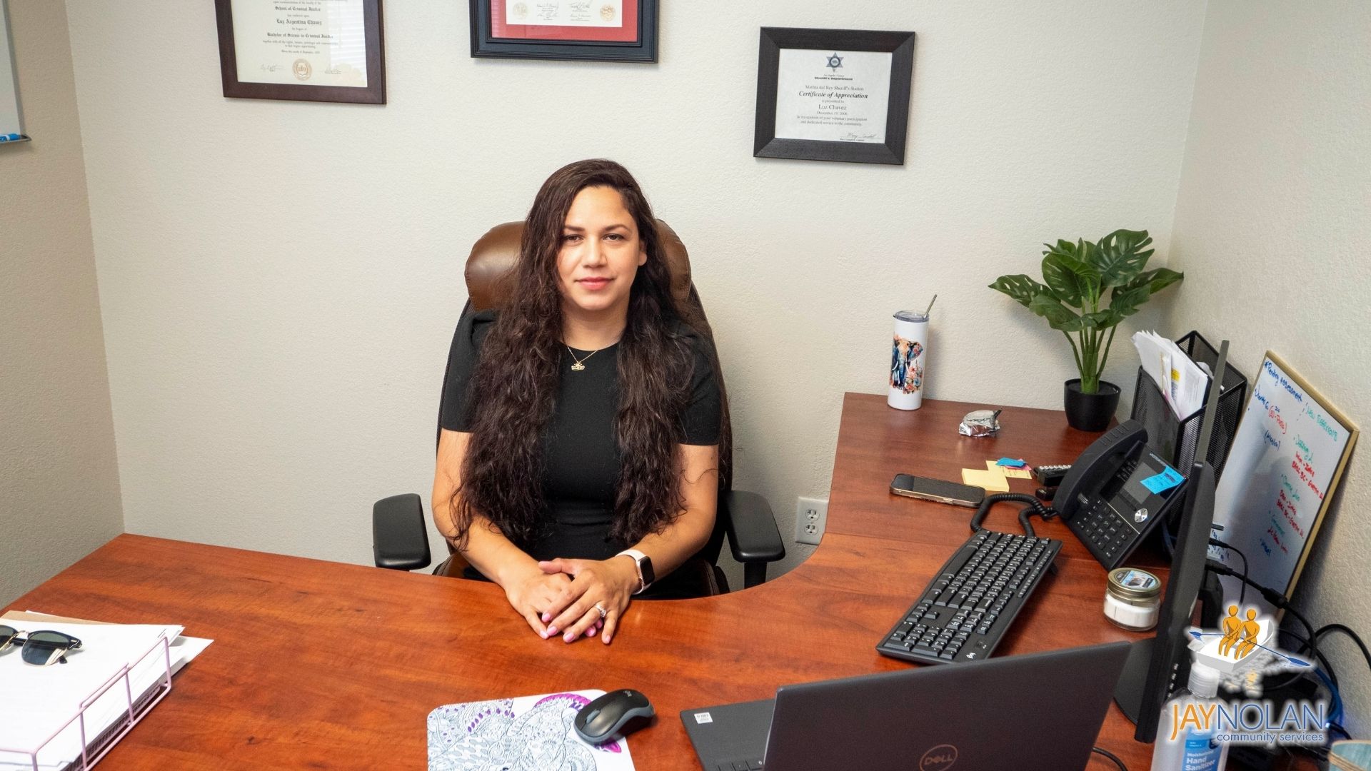 Chief Program Officer Luz Chavez, a Latina woman with long curly brown hair, sitting at a desk in an office.