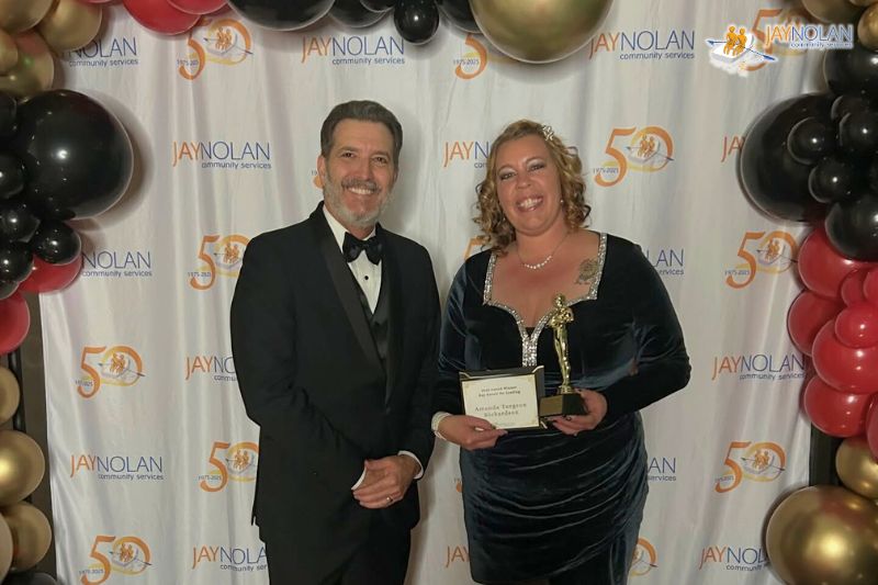 Jay Nolan staff Amanda posing with the Jay Nolan CEO while holding a Key Results Award trophy.