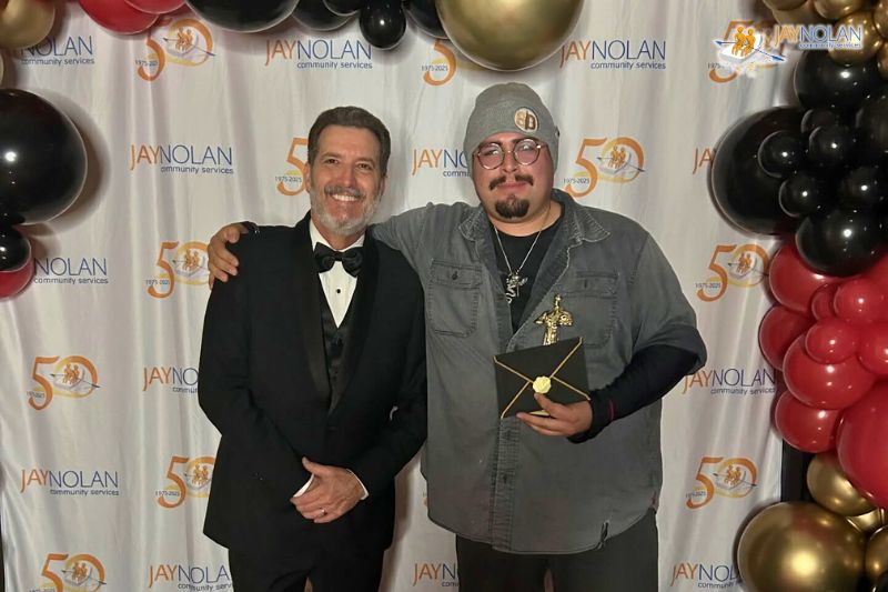 Jay Nolan staff Jose posing with the Jay Nolan CEO while holding a Key Results Award trophy.