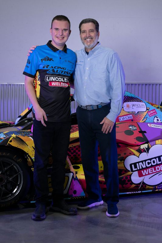 CEO Edward Amey of Jay Nolan Community Services and Austin Riley of Racing with Autism pose in front of Austin's 2026 racecar