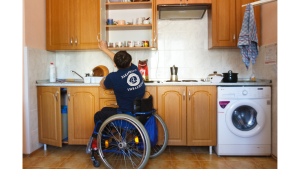 an individual in a wheelchair reaching for a cupboard in the kitchen