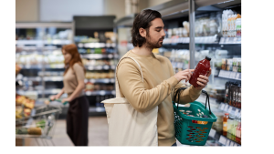 a male grocery shopper reading the nutrition label on a bottle