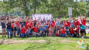 A group of Jay Nolan staff posing with their arms in the air for a group photo at the Autism Acceptance Picnic