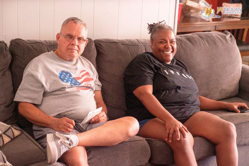 A an older Caucasian man sitting on a couch next to an African American woman who is his direct support professional staff