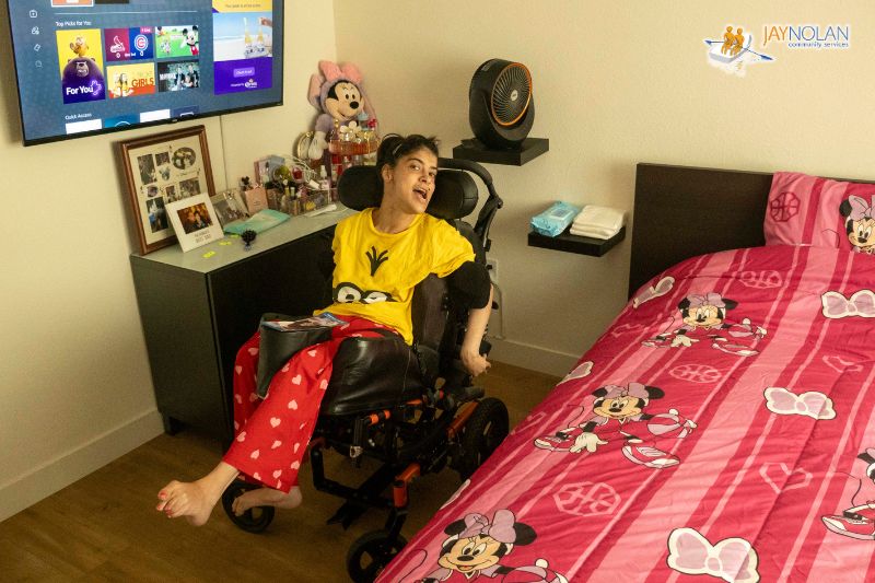 A woman with Cerebral Palsy receiving Supported Living services in a wheelchair in her own bedroom.